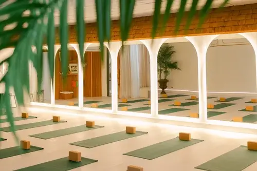 Wellness studio at CC Studio in Sebring, featuring green yoga mats, wooden blocks, arched mirrors, and warm, calming lighting.