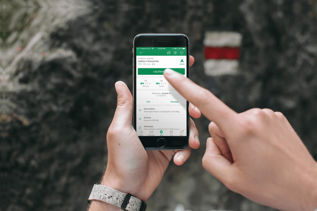 Close up of hands using Geocaching app on iPhone
