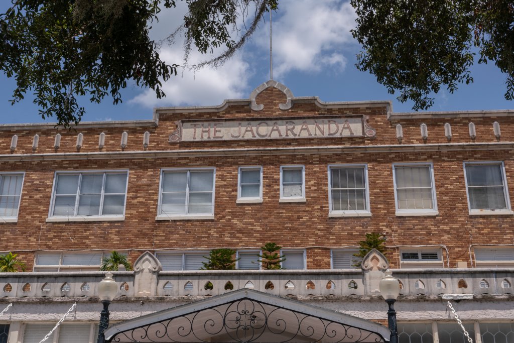 Front face of the Hotel Jacaranda showing its multiple white windows, hotel name, and brick exterior.