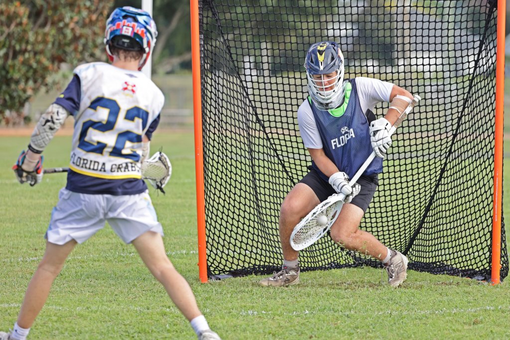 Two youth mens lacrosse players face off at the goal