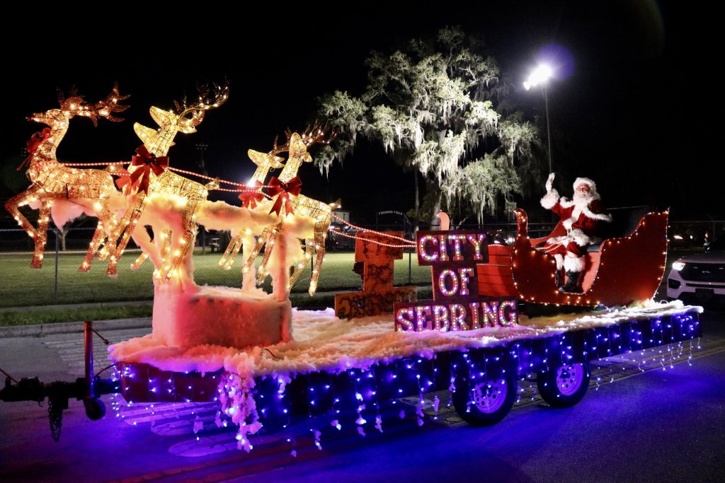 Santa Claus waves from his sleigh being pulled by reindeer atop a trailer as part of the city of Sebring, Fl Annual Christmas Parade