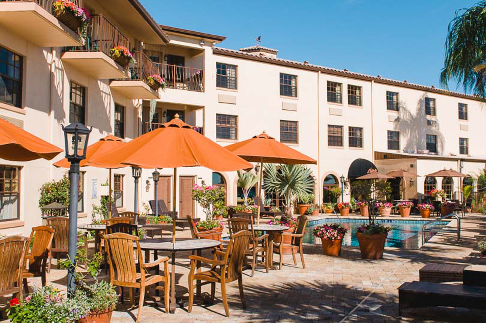 Patio with swimming pool, tables, umbrellas and chairs at the Inn On The Lakes