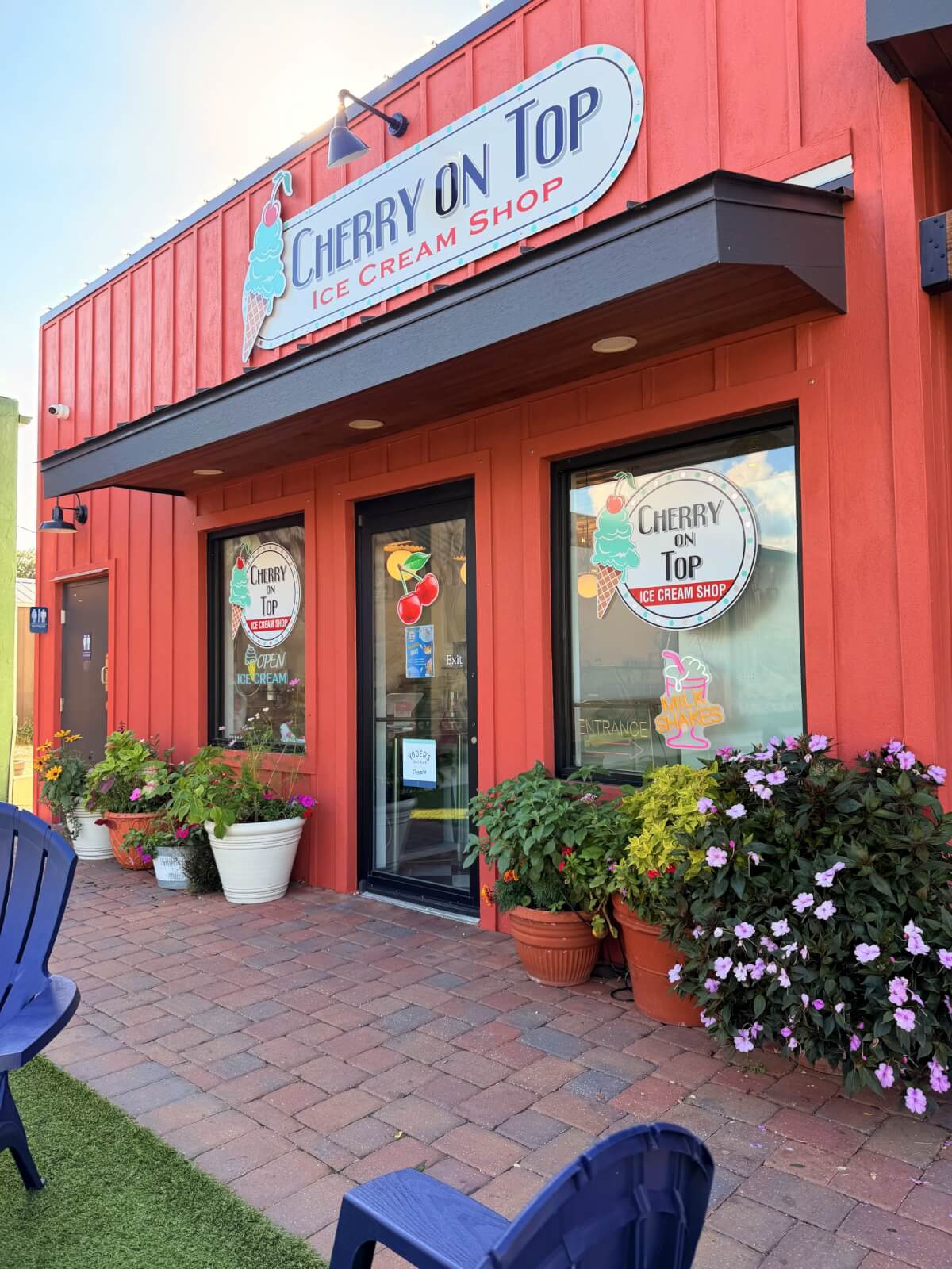 Red wooden exterior of an ice cream shop in Lake Placid, Florida, featuring ice cream cone decals and business logos on the windows, door, and signage.
