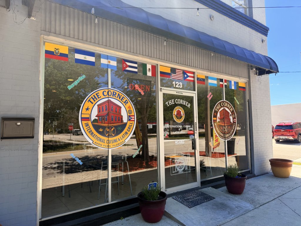 Storefront exterior showing big windows with restaurant decals and a string of flags above windows