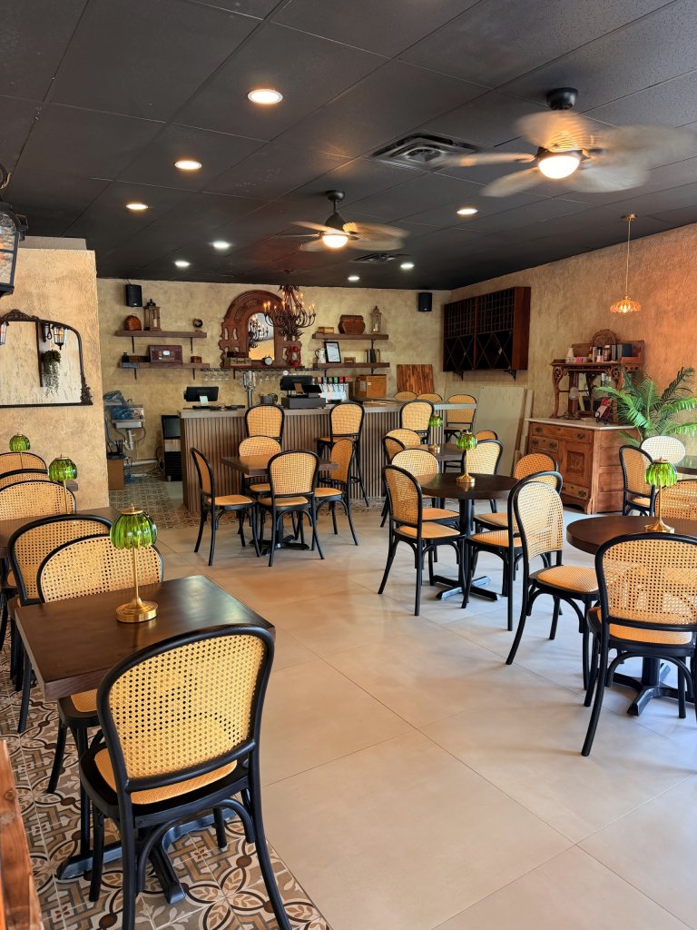 warm beige interior design with cafe dining style tables, green glass lanterns at each table, black ceiling with leaflet fans