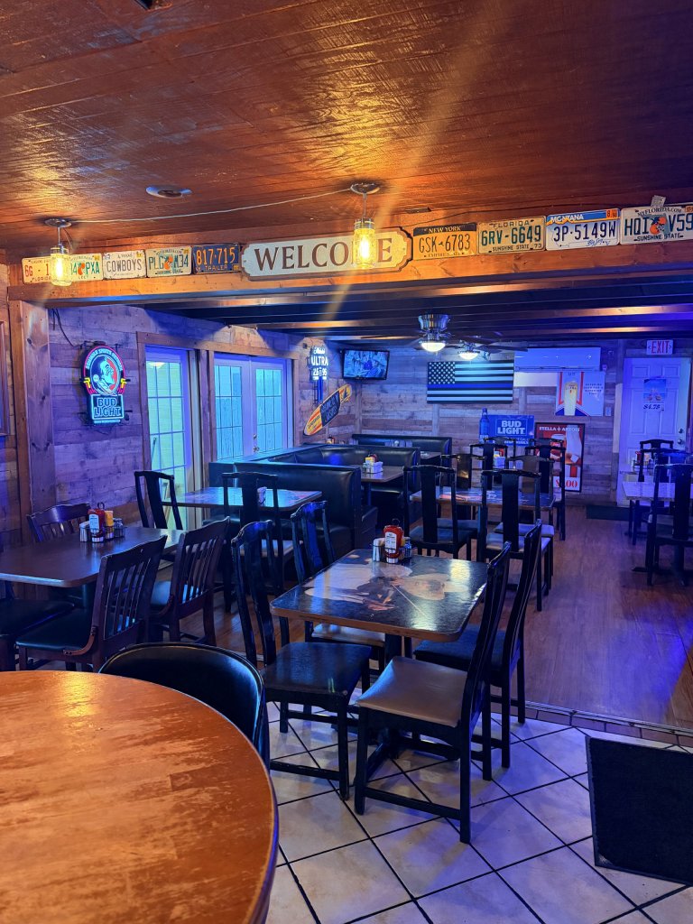 Some of the interior dining area of Jaxson's showcasing both booths and tables with license plate decoration on the above ceiling.