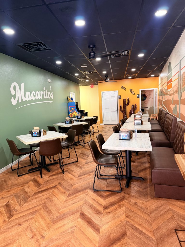 Interior seating of establishment showcasing brown leather booths and chairs along a decorative painted wall displaying the name of the restaurant. 