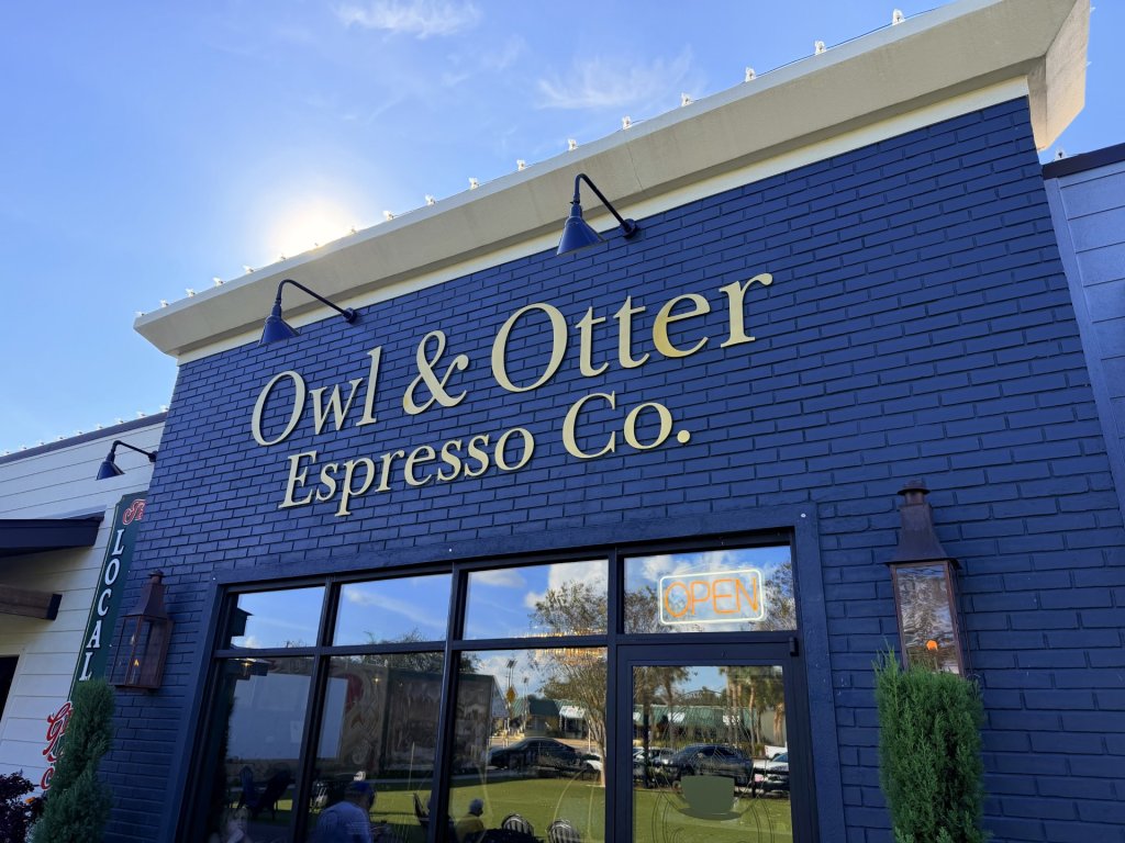 Modern blue brick storefront in Journal Plaza, Lake Placid, FL, with elegant gold-accented signage highlighting the establishment’s name against the vibrant exterior.