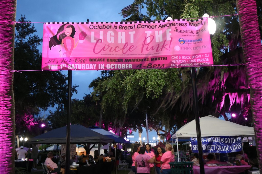 Pink banner hanging at the circle in sebring advertising "Light the Circle Pink" underneath it shows the booths that are set up during this event.