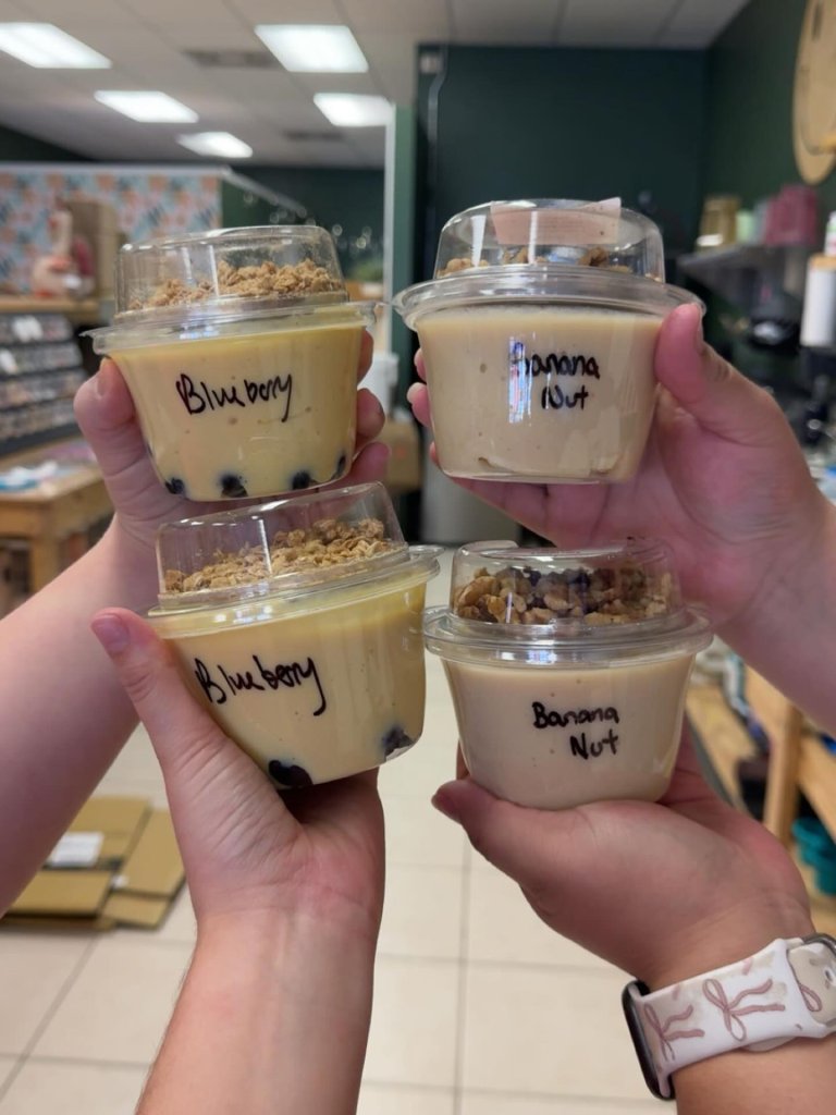 Hands holding blueberry and banana nut parfait cups at Thankful Hearts Nutrition in Avon Park, Florida.