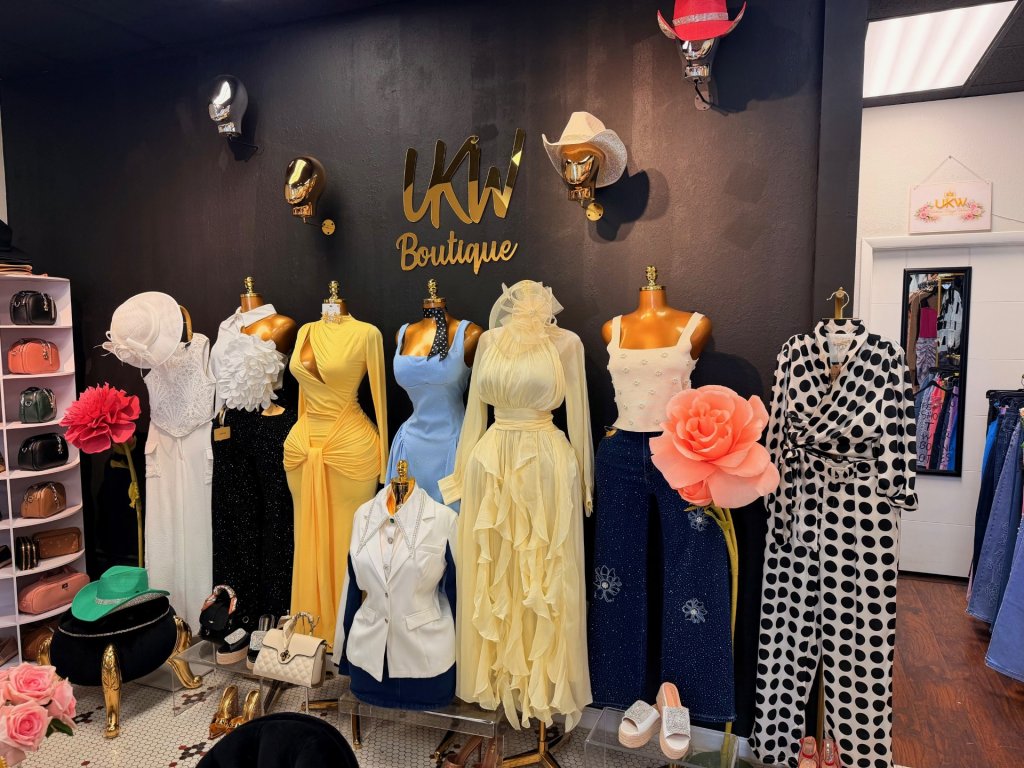UKW Boutique gold signage on a black wall with a line up of mannequins each dressed in different outfits that are offered in store.